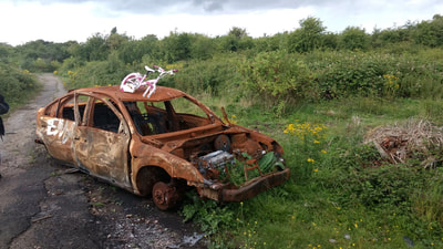Child's pink bike abandoned on top of burnt out car in Dartford, Kent